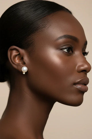 Close-up of a woman wearing pearl earrings against a beige background