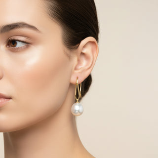 Gold earrings with large white pearls on a white background