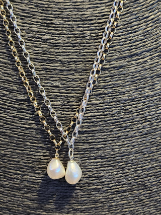Two pearl necklaces on a textured surface