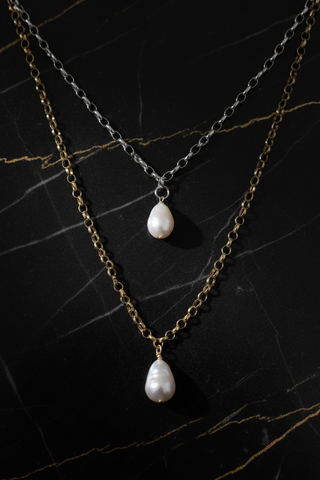Two pearl necklace chains on a dark marble surface