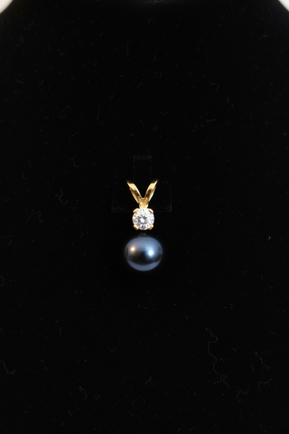 Black pearl and gold pendant on a black background