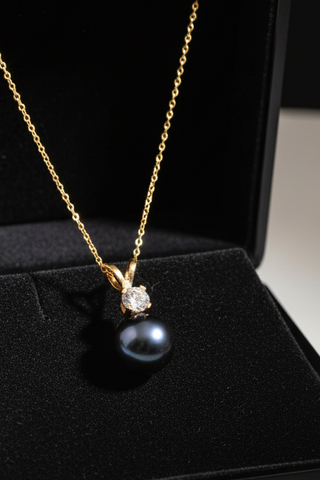 Gold necklace with a black pearl and diamond pendant on a black background