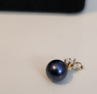 Black pearl earring on a light gray background