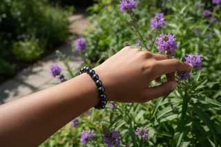 Hand wearing a black beaded bracelet with a bouquet of red roses and gold leaves on a dark background