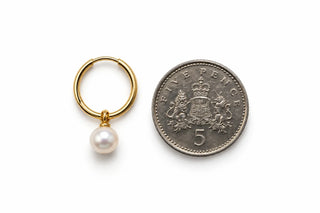 14K yellow gold endless hoop earring with a 12mm white freshwater pearl next to a 5p coin.