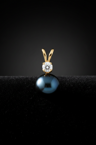 Gold pendant with a blueish black pearl on a black background
