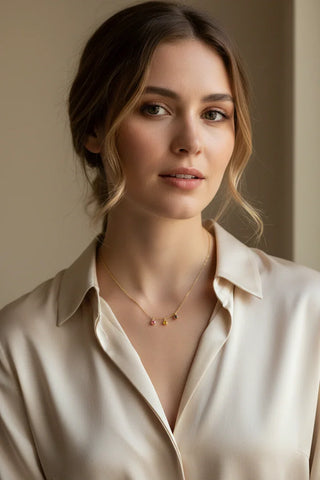 Woman wearing a beige blouse and necklace with small pendants.