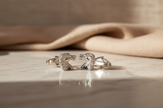 Sterling silver andulsian-shaped cufflinks on a wooden surface with a beige fabric background