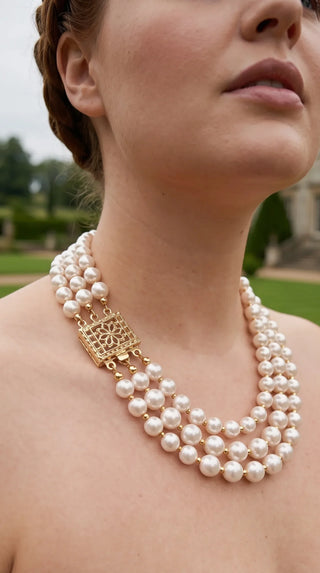 Close up of a woman wearing triple strand pearl necklace