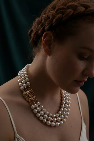 Woman wearing a multi-strand handcrafted pearl necklace with a gold clasp.