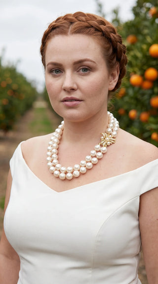 Woman with red braided hair wearing a double strand pearl necklace with gold clasp