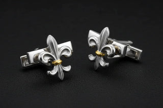 Pair of silver fleur-de-lis cufflinks on a black background