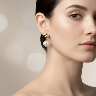 Pair of pearl earrings with gold and diamond accents on a white background
