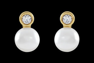 Pair of pearl earrings with gold and diamond accents on a black background