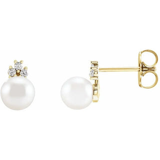 Gold stud earrings with white pearls and three small diamonds on a white background