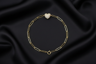 Yellow Gold paperclip chain bracelet with diamond heart charm on black satin background