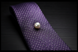 Purple tie with a pearl pin on a dark background