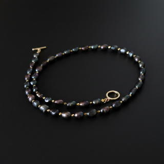 Pearl necklace with gold clasp on a dark surface