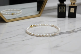 A pearl necklace with gold accents rests gracefully on a dressing table.