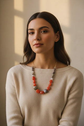 Woman wearing a beige sweater and a colorful necklace indoors.