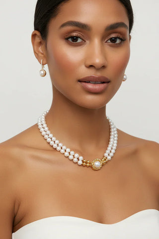 Woman wearing a pearl necklace and earrings on a plain background