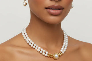 Pearl necklace with a gold clasp worn by a model against a neutral background
