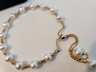 Handcrafted pearl slider bracelet with gold beads on a light background