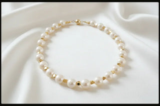 Handcrafted pearl and gold bead necklace on white satin fabric