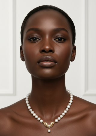 Woman wearing a pearl necklace with a gold pendant against a white background