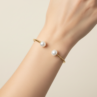 Gold bracelet with pearls on a wrist against a beige background
