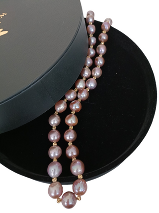 Pearl necklace on a black stand with a white background