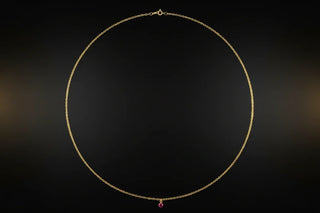 Gold necklace with a red ruby gemstone on a dark background