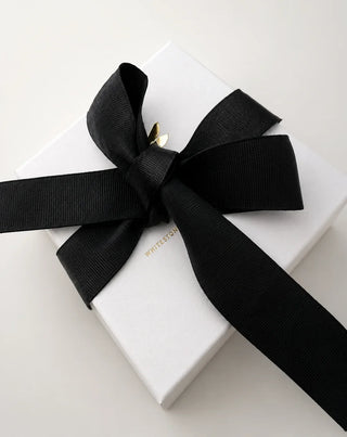 White luxury jewelry gift box with a wide black grosgrain ribbon bow.