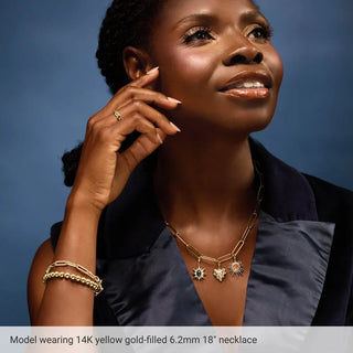 Woman wearing a 14K gold-filled paperclip chain necklace with three decorative pendants.