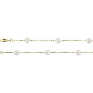 Gold chain necklace with evenly spaced white pearls, lobster clasp close-up