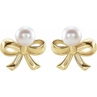 Gold bow-shaped earrings with pearls on a white background