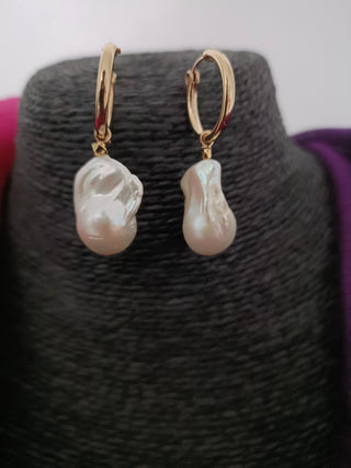 Pearl earrings on a black jewelry display with a white background