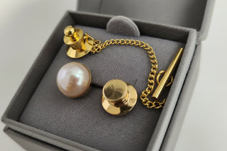 A pearl Gold Tie Tack in a box