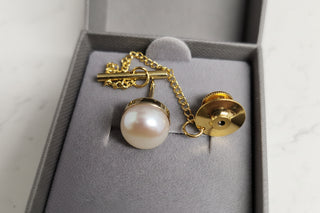 Gold Pearl Tie Tack  on a gray background