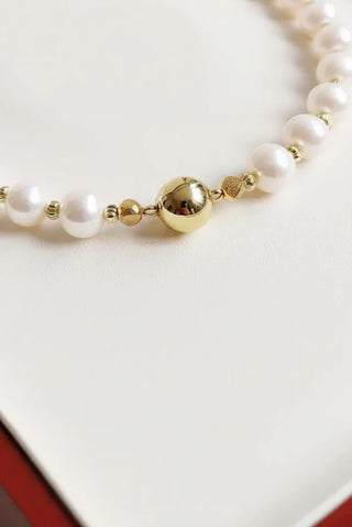 Close-up of a handcrafted pearl necklace with a polished gold bead accent