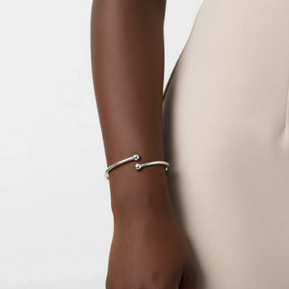 Silver bracelet on a wrist with a neutral background