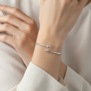 Silver bracelet on a person's wrist with a plain background