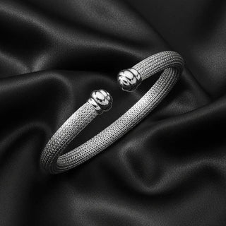 Sterling silver cuff bracelet with textured band and polished ends on black satin fabric