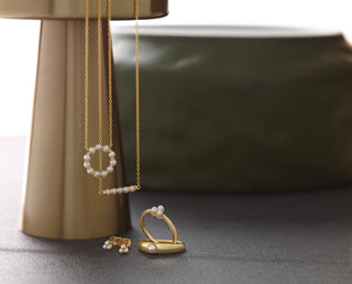 Gold jewelry set with pearls on a dark surface