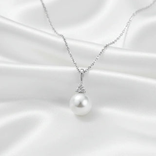A white gold necklace adorned with sparkling diamond accents on a soft silk fabric